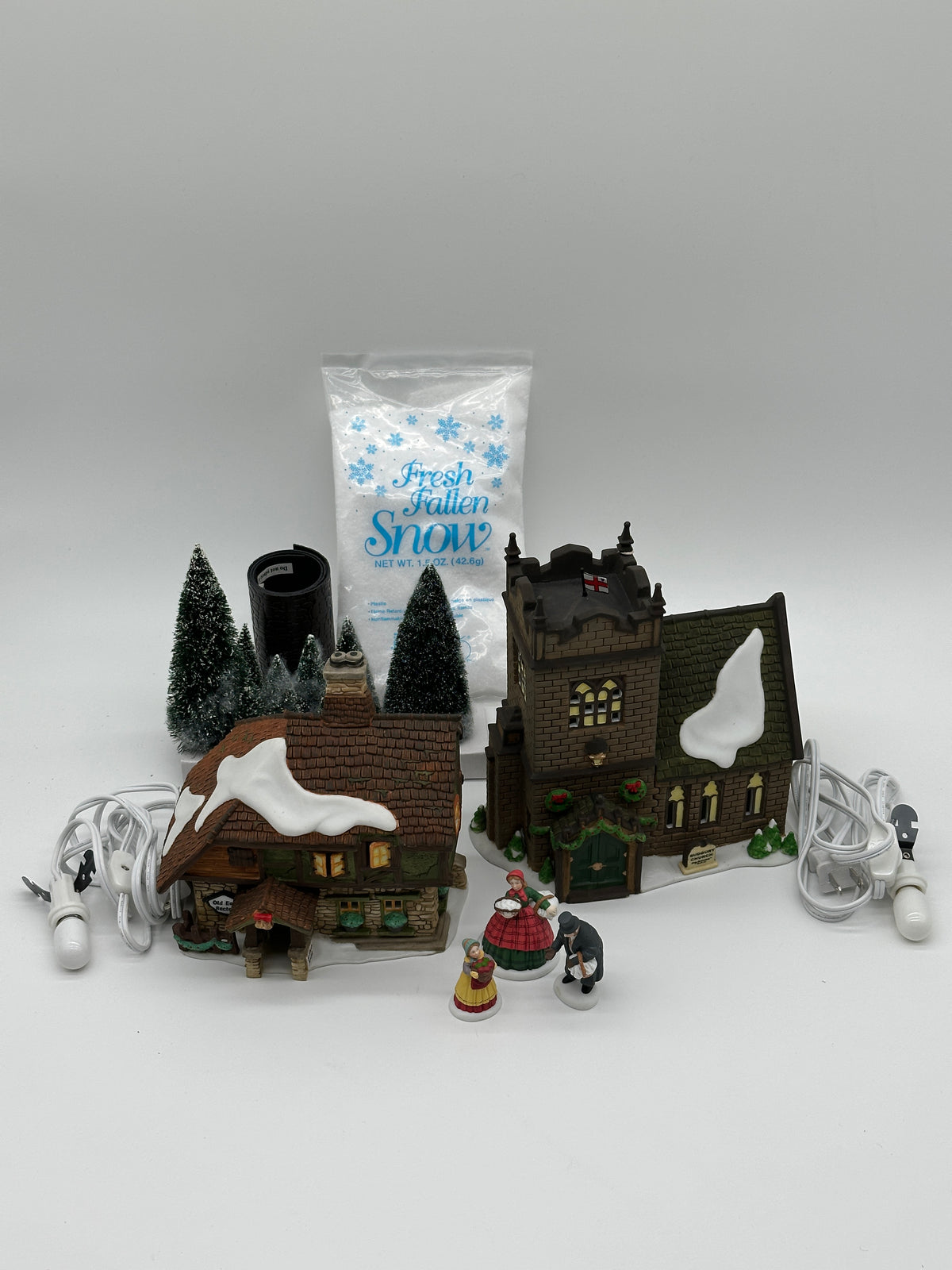 Department 56 The Spirit of Giving Start A Tradition set laid out: Sudbury Church, Old East Rectory, three figures, six sisal trees, bag of snow and both light cords